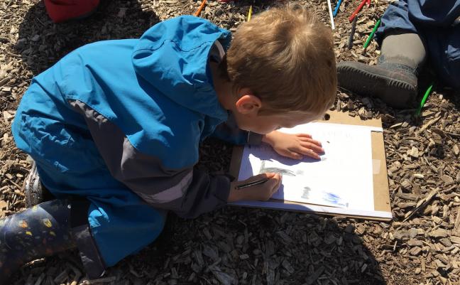 A photo of a student creating and labeling a map of our outdoor classroom space provides evidence of his spatial awareness, fine motor, and writing skills. Image courtesy of Anna Dutke.